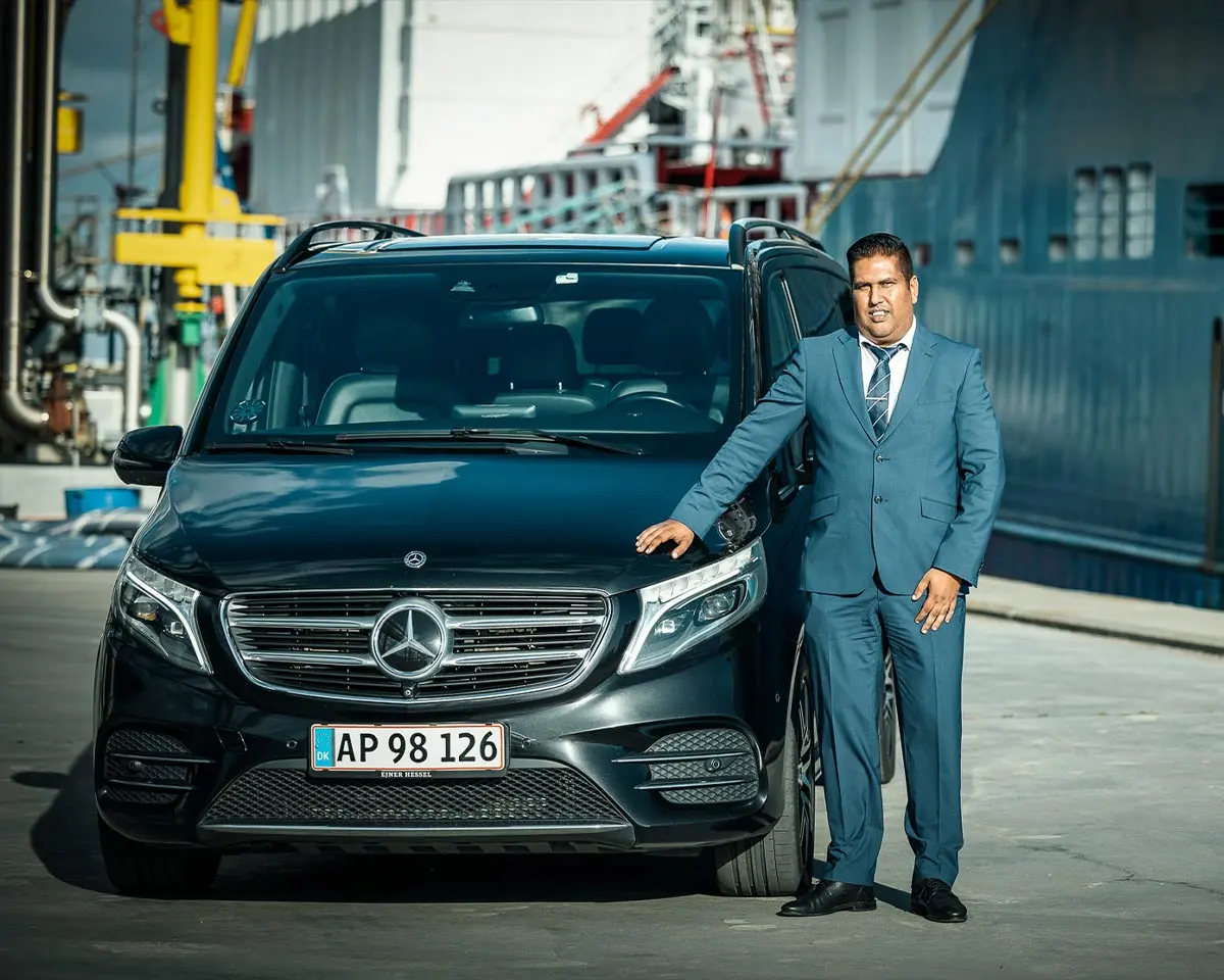 Airport Transfer Copenhagen chauffeur beside a Mercedes V-Class